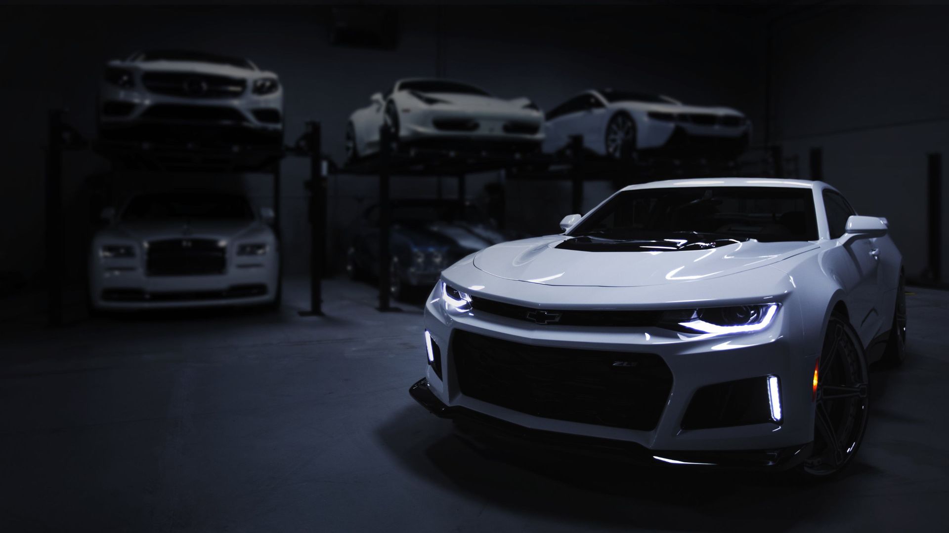 White Chevrolet Camaro in a dimly lit garage with other luxury cars.