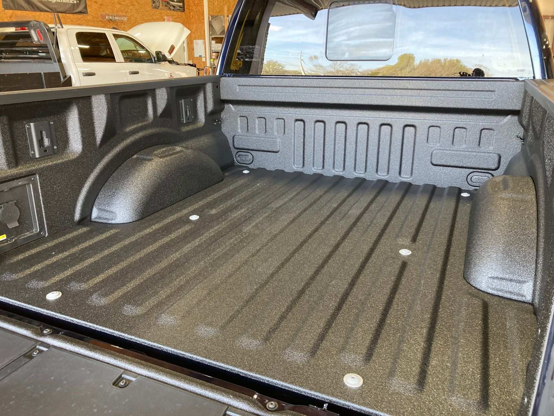 Black truck bed with textured coating. Metal tie-down points along the sides and bed.