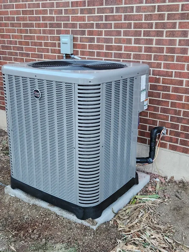 A large air conditioner is sitting outside of a brick building.
