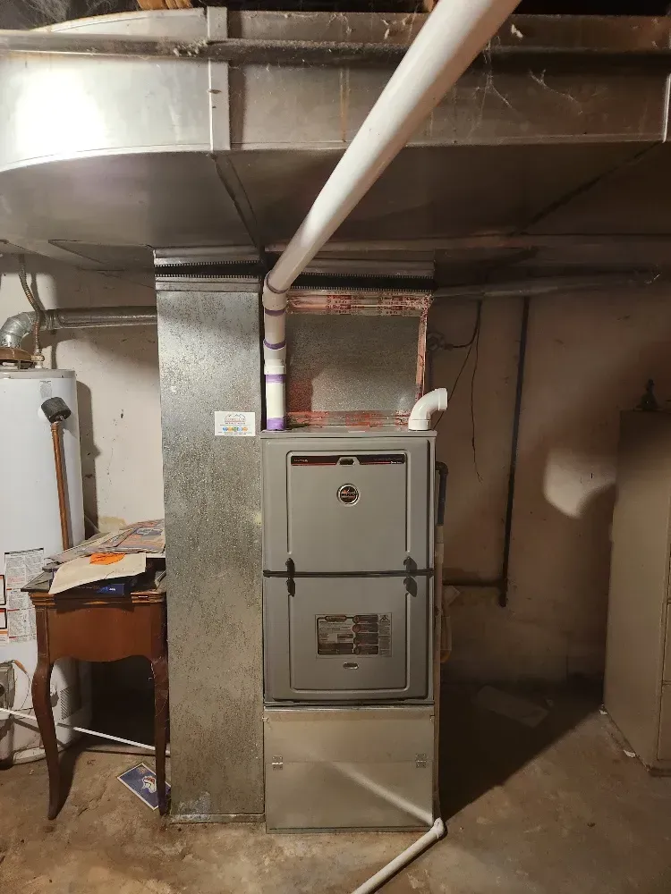 A furnace is sitting in a basement next to a table.