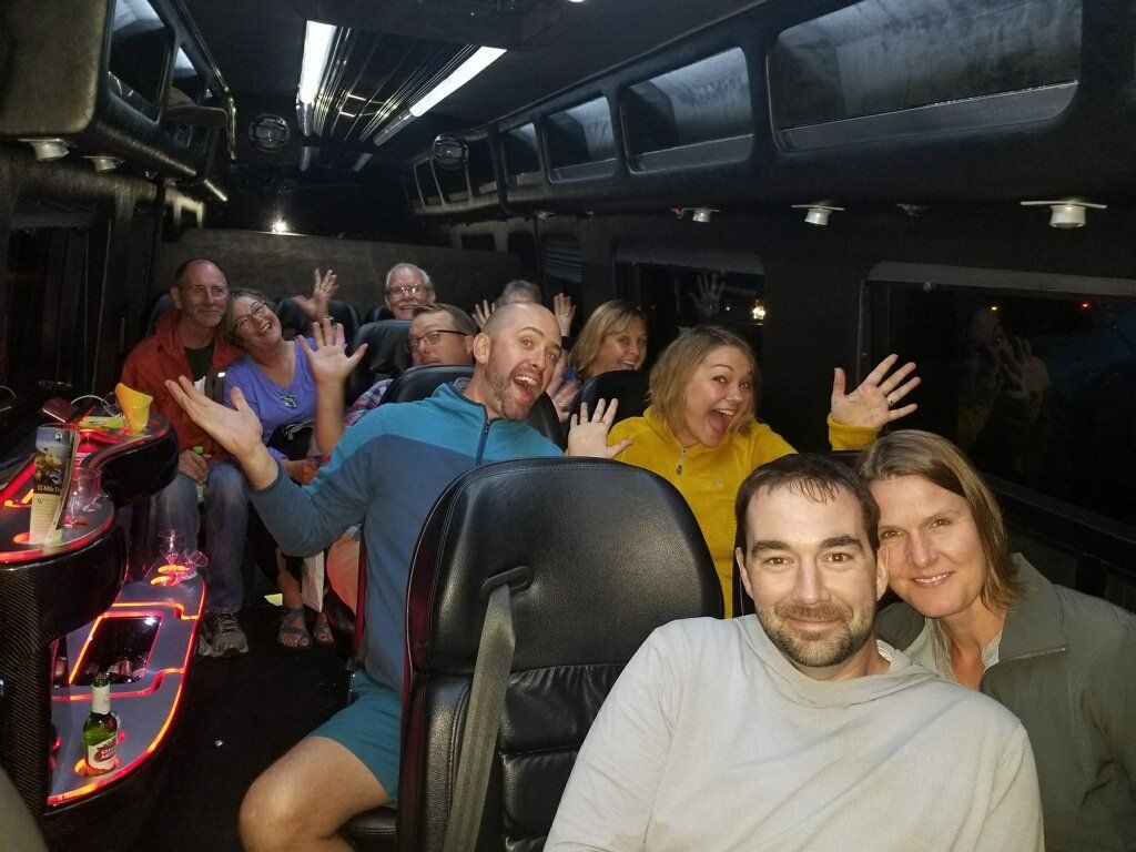 A group of people are sitting on a bus waving at the camera.