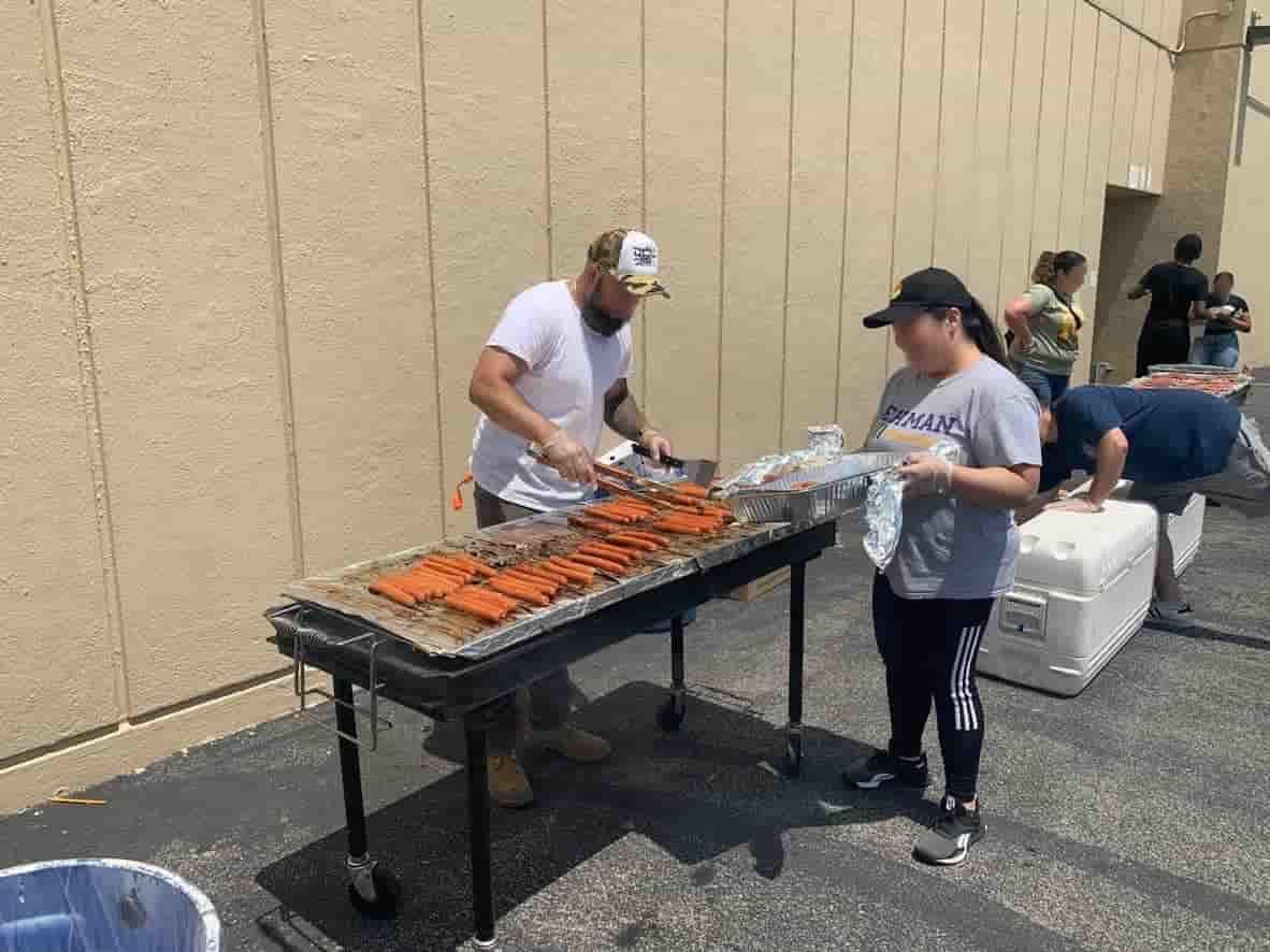 A group of people are standing around a table cooking food.
