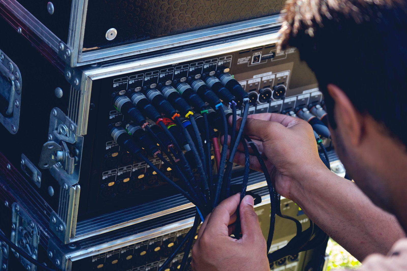 A man is working on a mixer with a bunch of wires coming out of it.