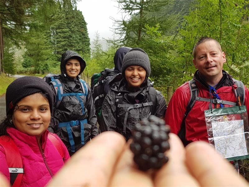 A person is holding a blackberry in front of a group of people.