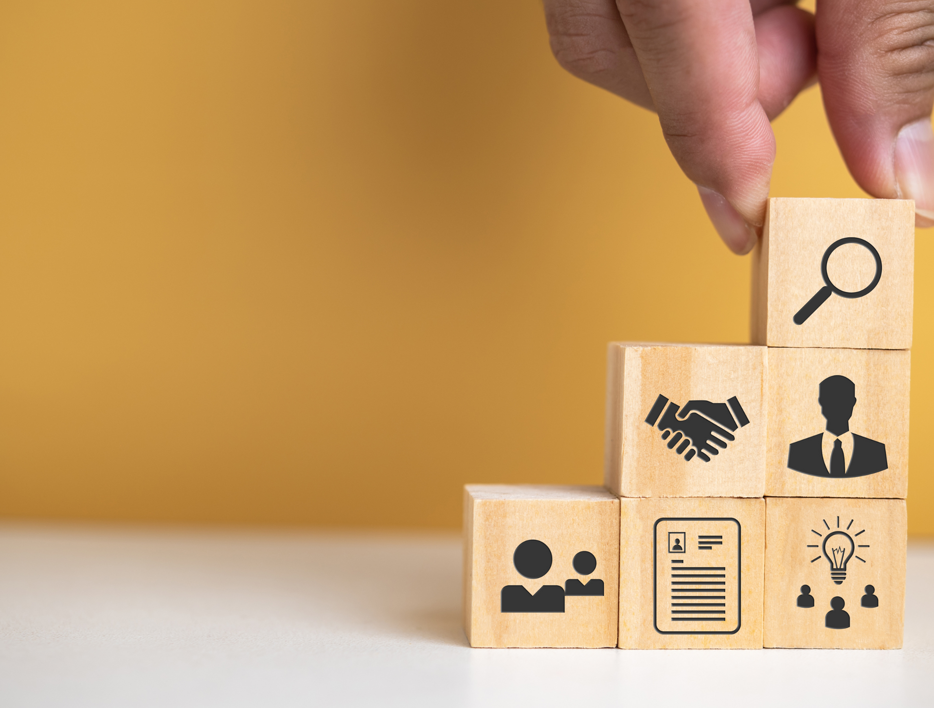 A person is stacking wooden blocks with icons on them.