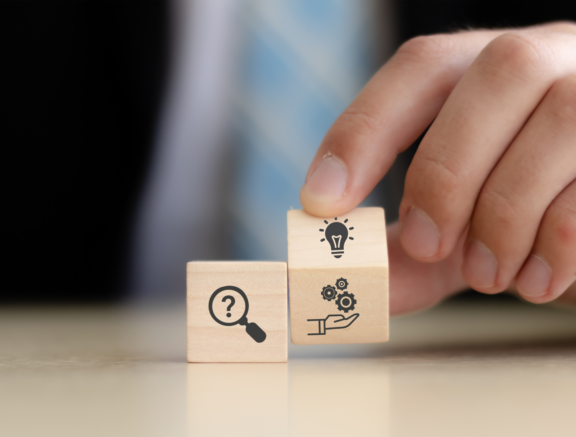 A person is stacking wooden blocks with icons on them.