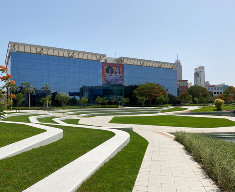 A large building with a lot of windows is surrounded by grass and trees