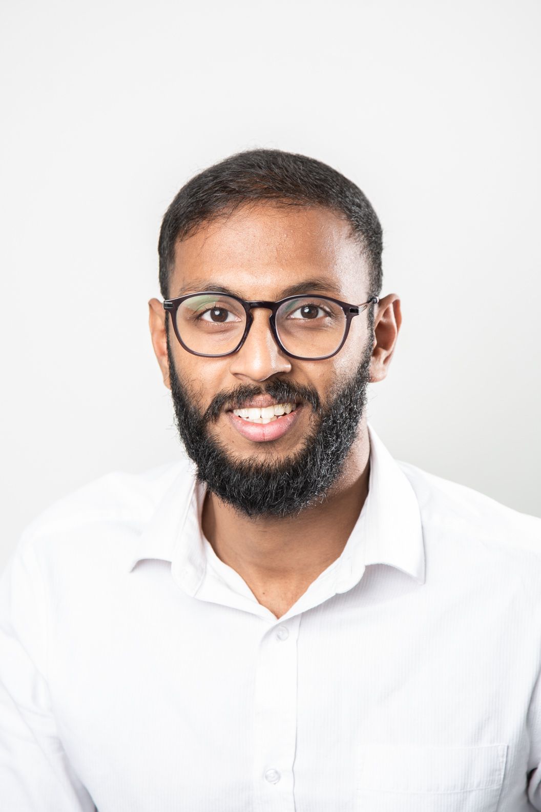 A man with a beard and glasses is smiling for the camera.