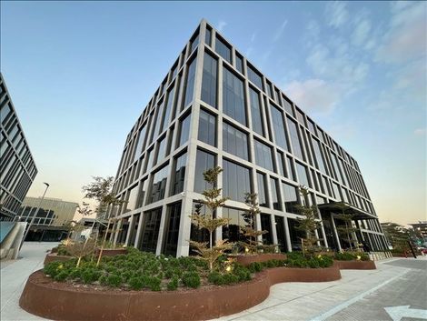 A tall building with a lot of windows is surrounded by trees