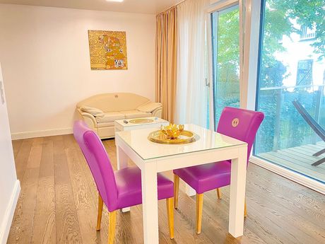 A dining room table with purple chairs and a couch in the background.