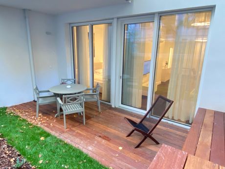 A wooden deck with a table and chairs in front of a sliding glass door.