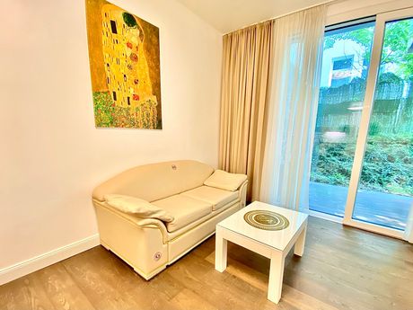 A living room with a couch , table and a painting on the wall.