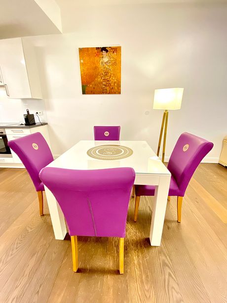 A dining room table with purple chairs and a lamp.