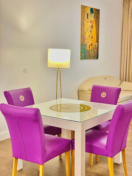 A dining room table with purple chairs and a lamp