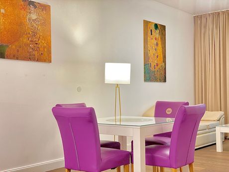 A dining room table with purple chairs and a lamp