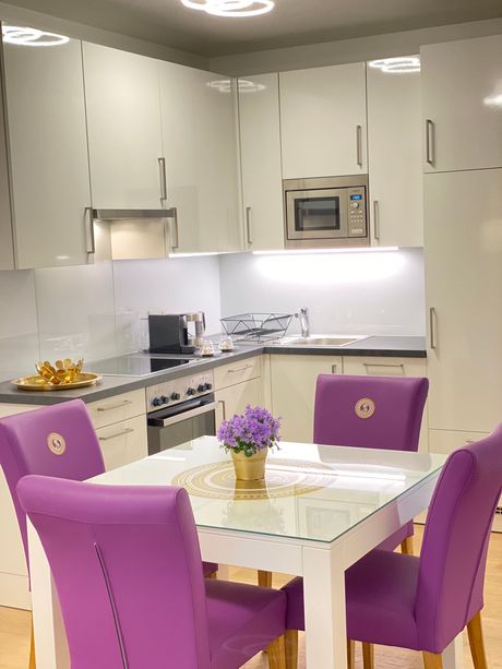 A kitchen with purple chairs and a table with purple flowers on it