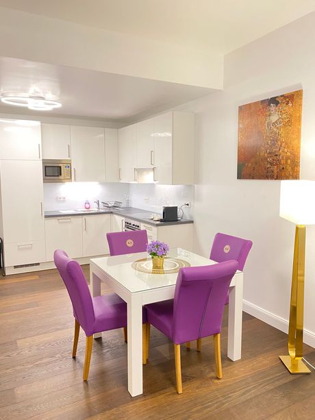 A dining room with purple chairs and a white table