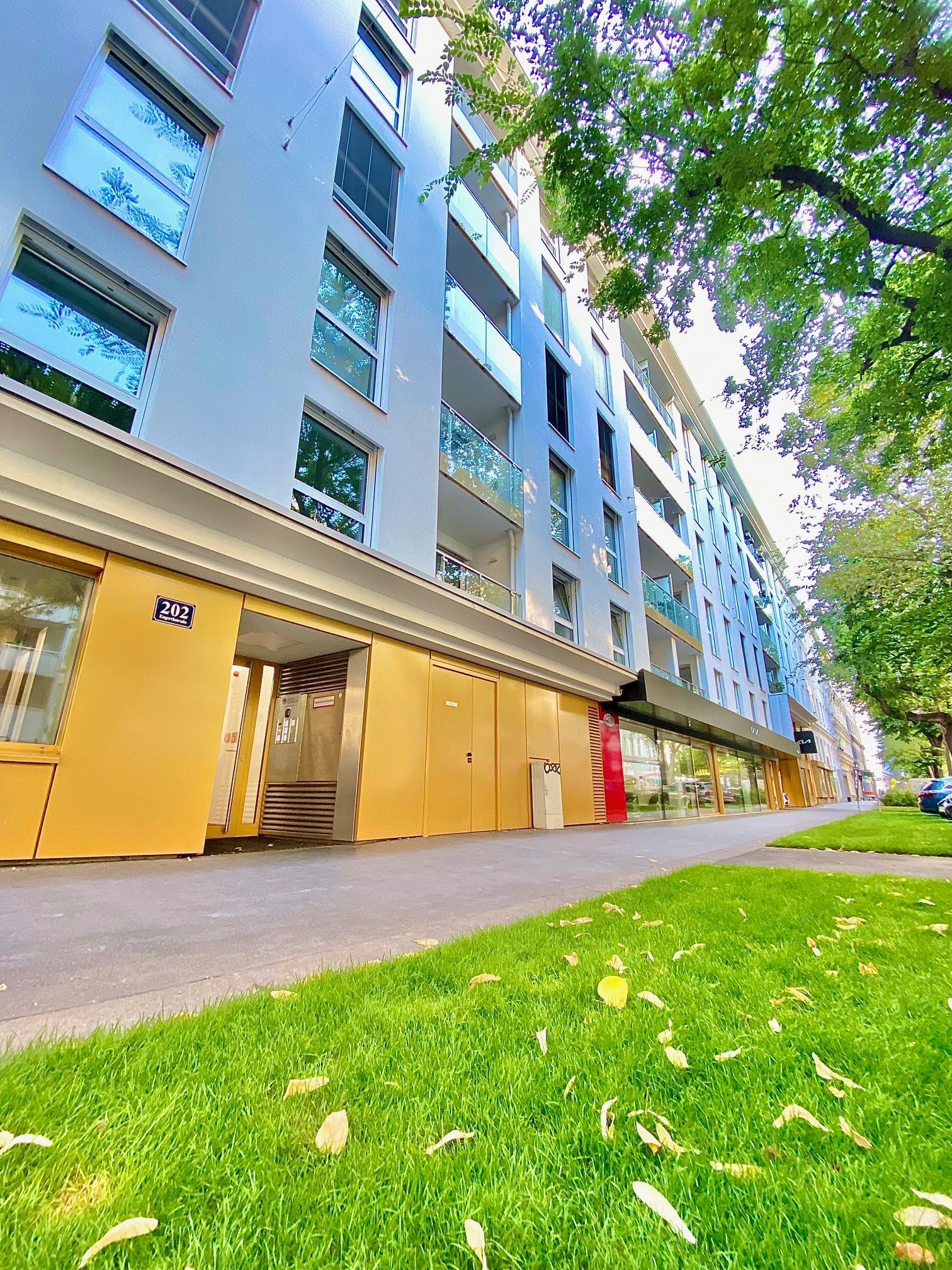 A large building with a lot of windows is surrounded by grass and trees.