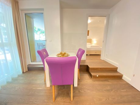 A dining room table with purple chairs in a room.