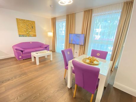 A living room with a purple couch , dining table and chairs.