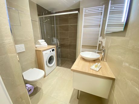 A bathroom with a toilet , sink , washer and dryer.