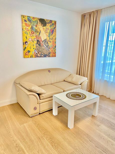 A living room with a couch , coffee table , and painting on the wall.