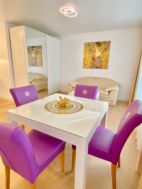 A dining room with purple chairs and a white table.