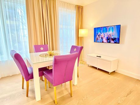 A dining room with a table and chairs and a flat screen tv on the wall.