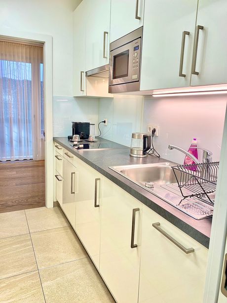 A kitchen with white cabinets , a sink , and a microwave.