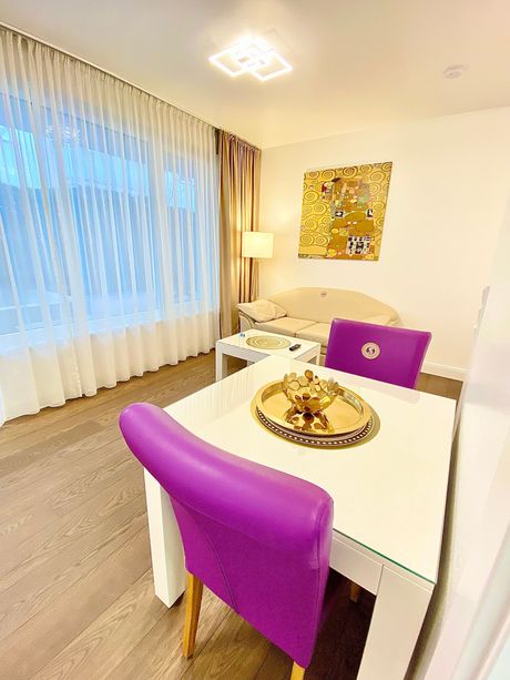 A living room with a dining table and purple chairs.