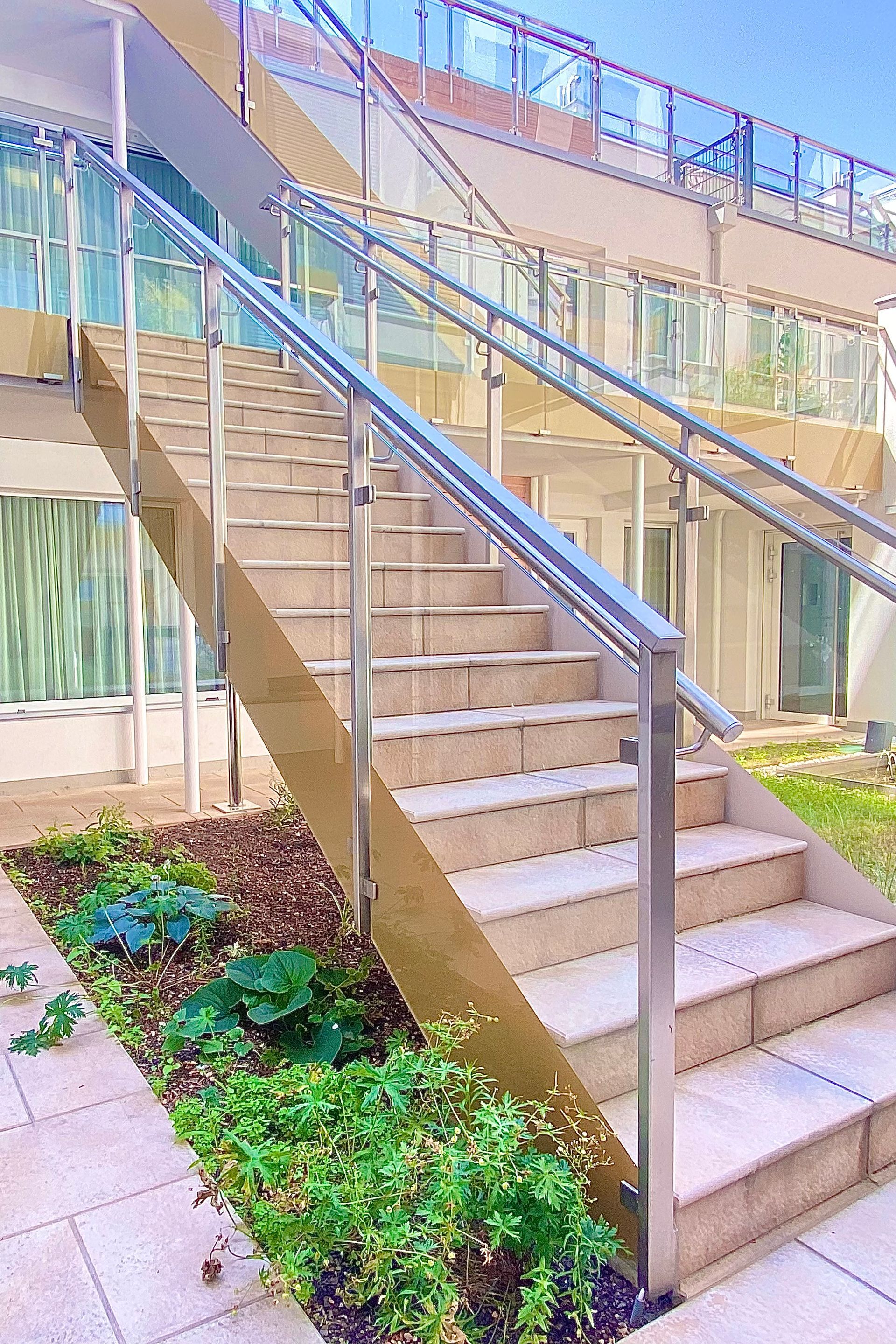 A set of stairs leading up to a building with a stainless steel railing.