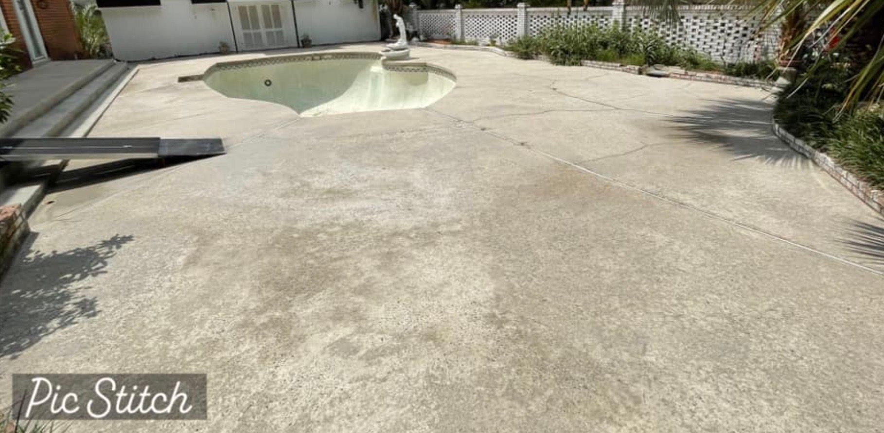Concrete backyard with an empty swimming pool.