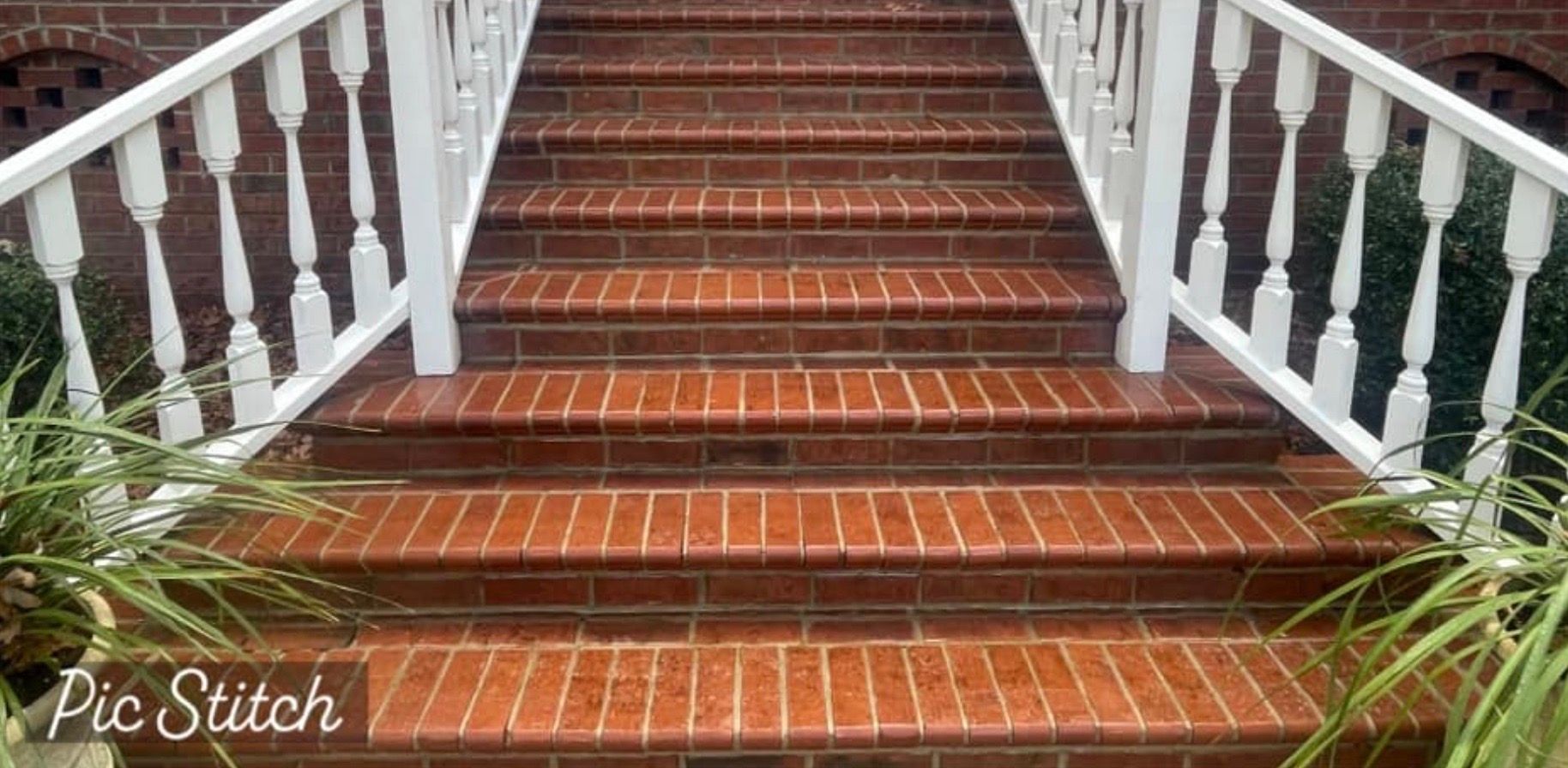 Brick steps with white railing. Green plants on the sides.
