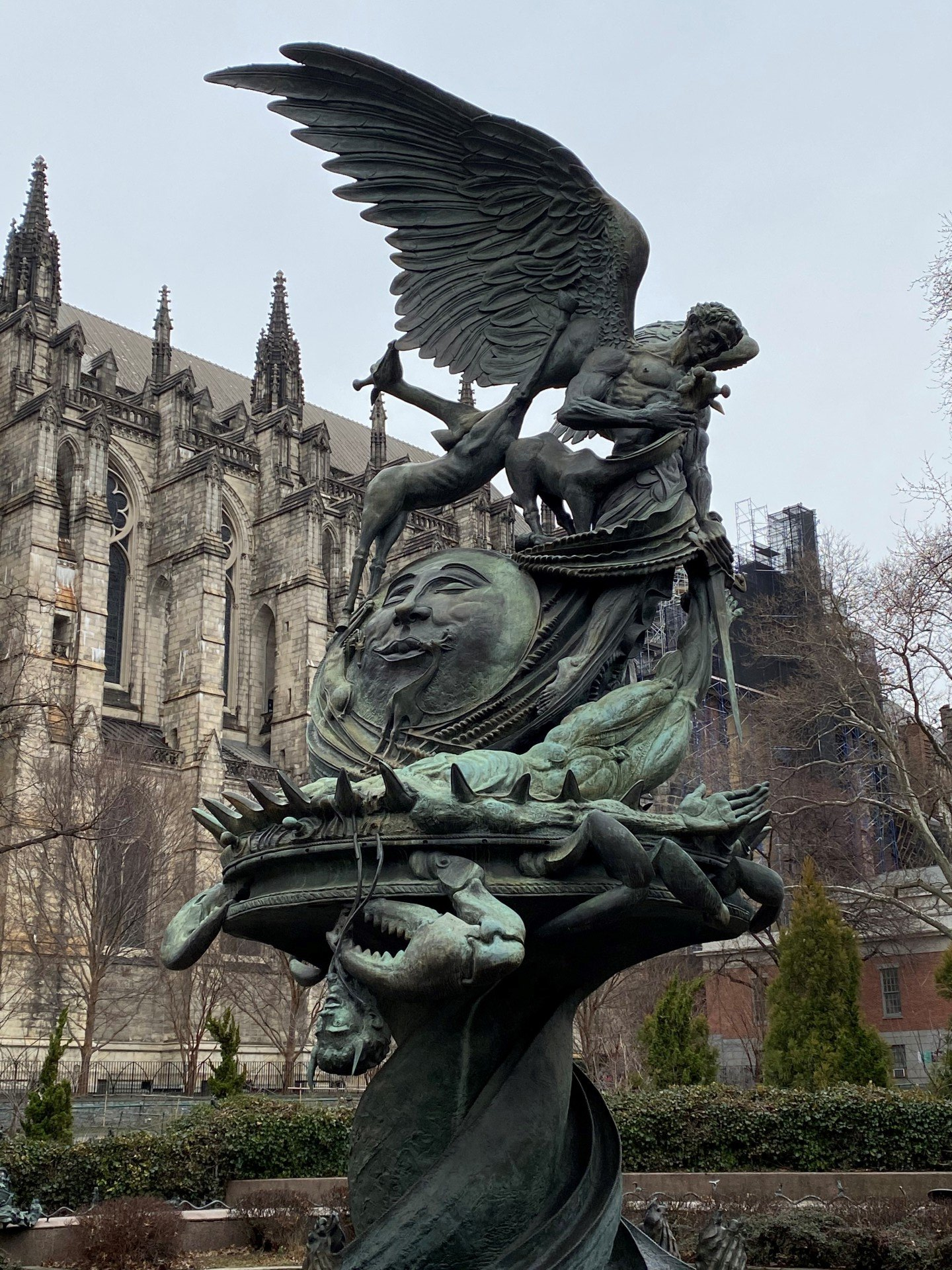 A statue of a man with wings is in front of a church.