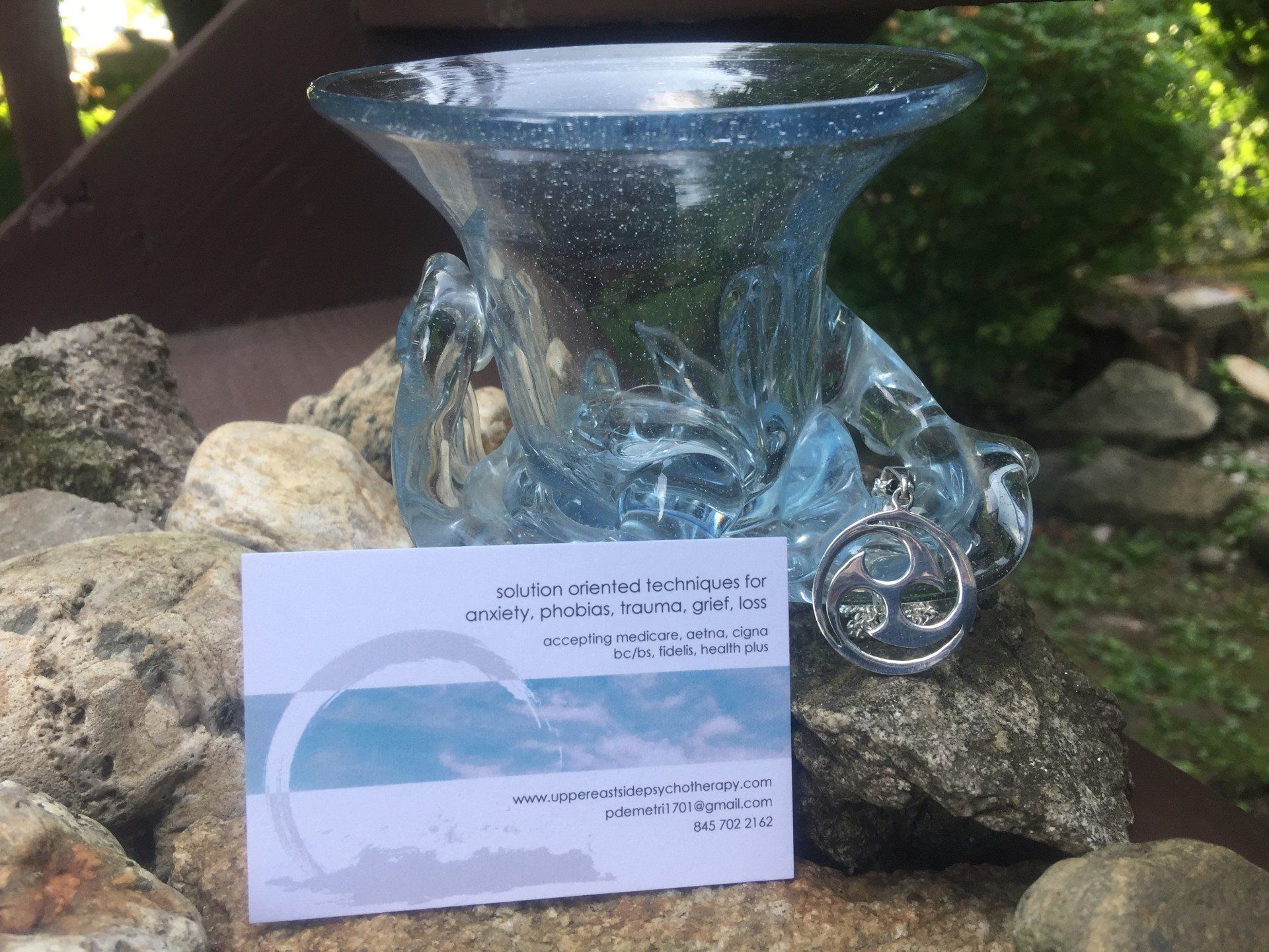 A business card is on a rock next to a glass vase