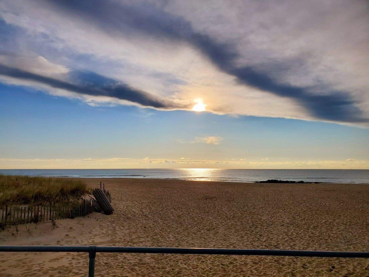 The sun is setting over the ocean on a cloudy day