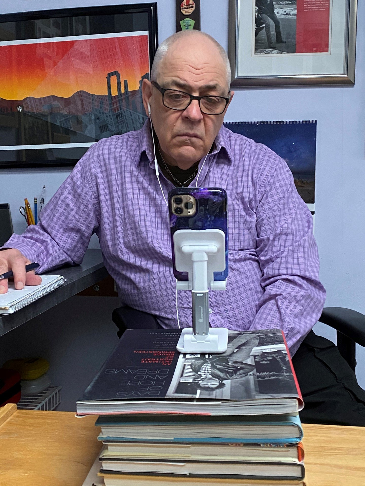 Peter is sitting at a desk with a stack of books and a cell phone.