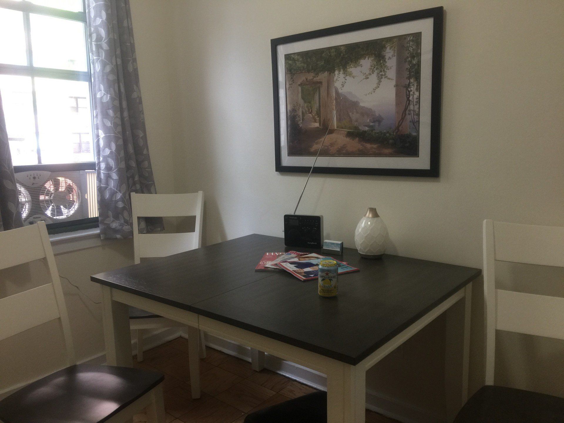 A dining room table with a picture on the wall above it