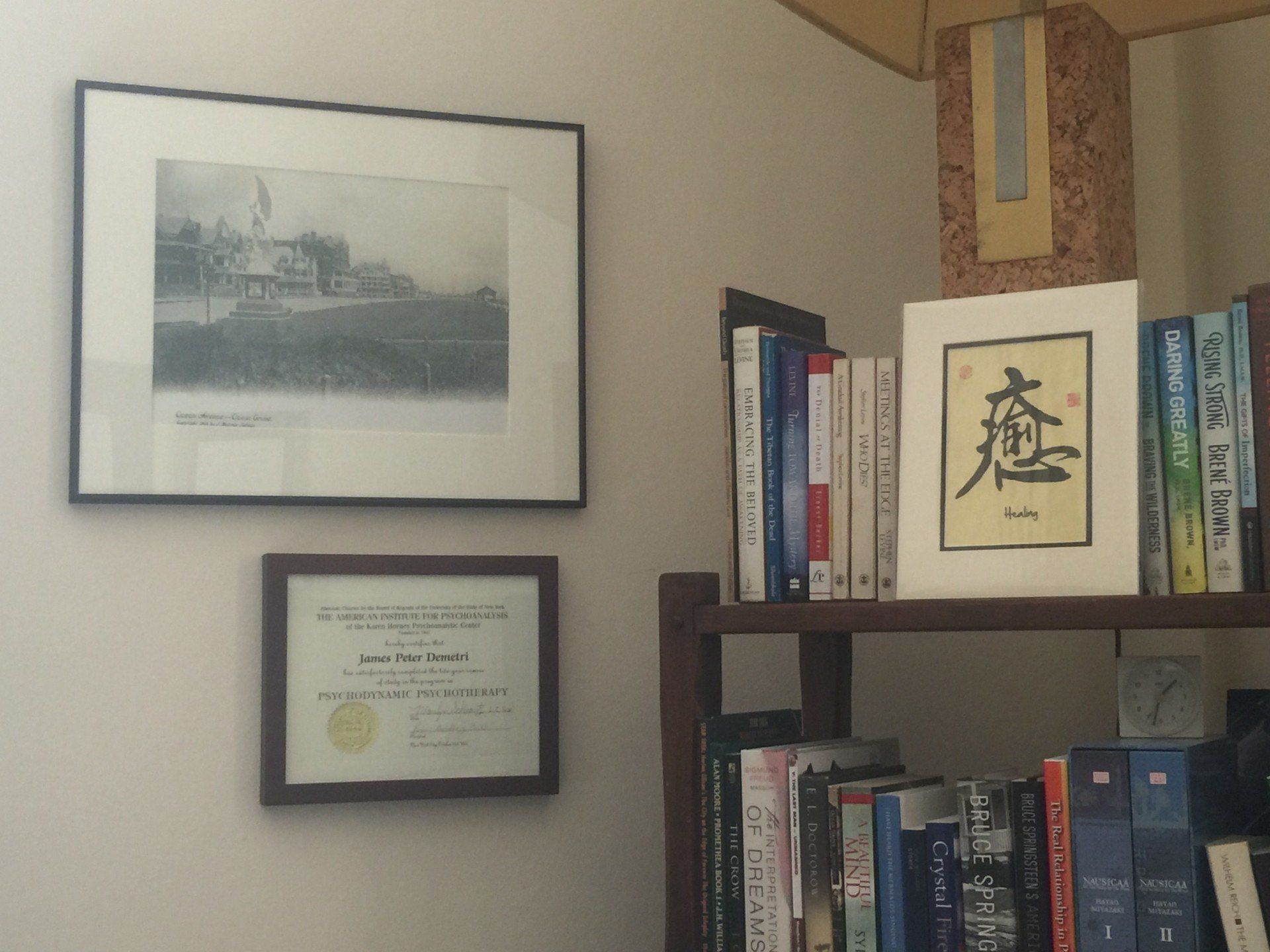 A framed picture hangs on a wall above a bookshelf
