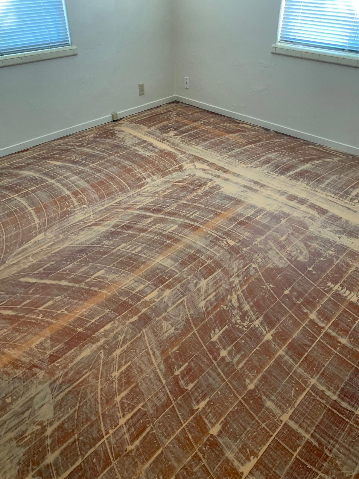 A room with a wooden floor and two windows.