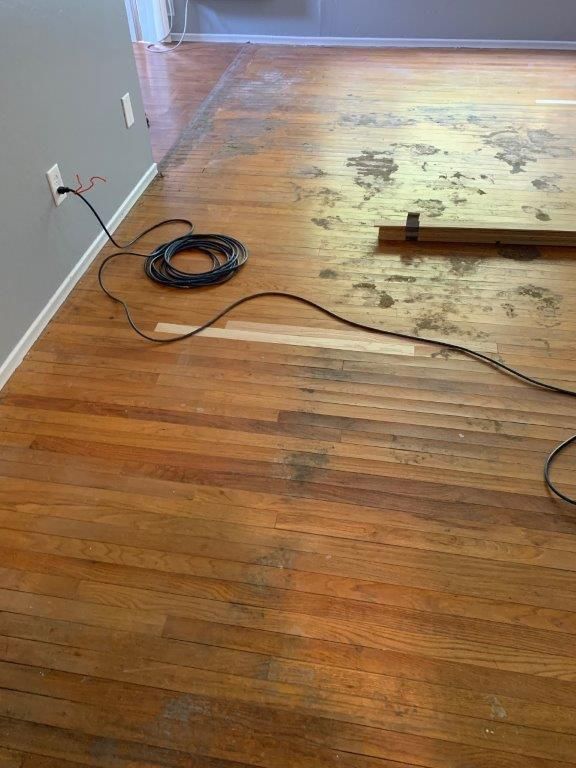 A wooden floor with a cord connected to it in a living room.