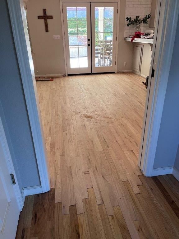 A wooden floor in a room with a cross on the wall.