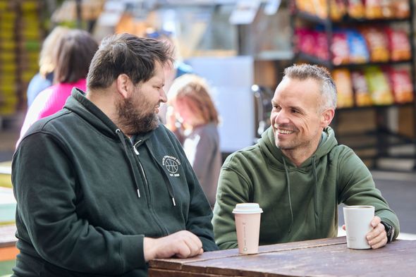 Two men are sitting with their coffee and chatting