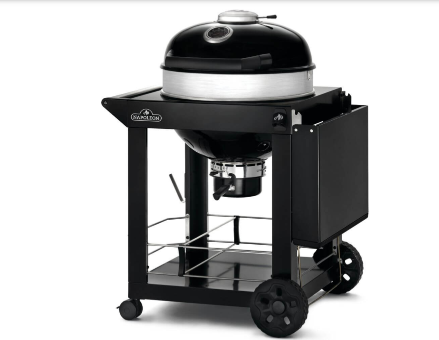 Barbecue a carbone Napoleon nero su carrello con ruote, dotato di coperchio arrotondato e vano portaoggetti laterale.