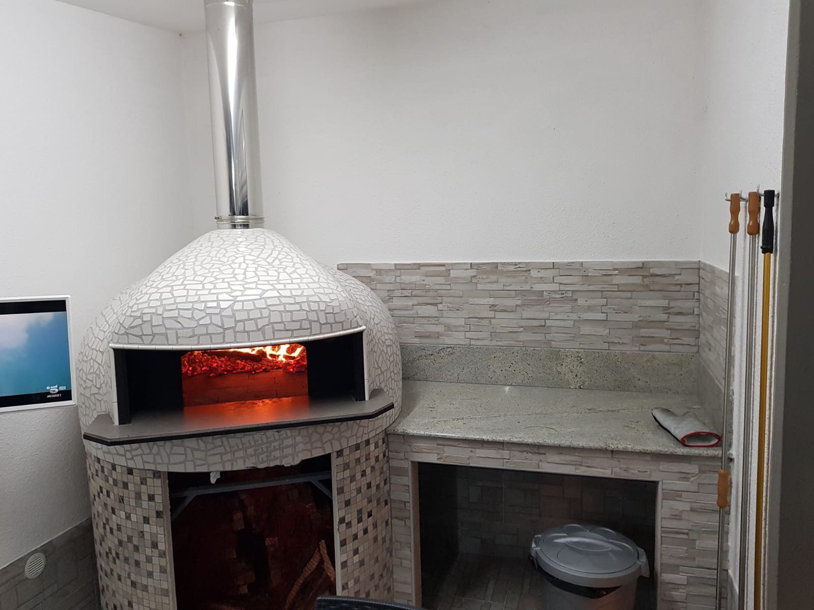 Forno per pizza con fuoco interno, integrato in un angolo con bancone.