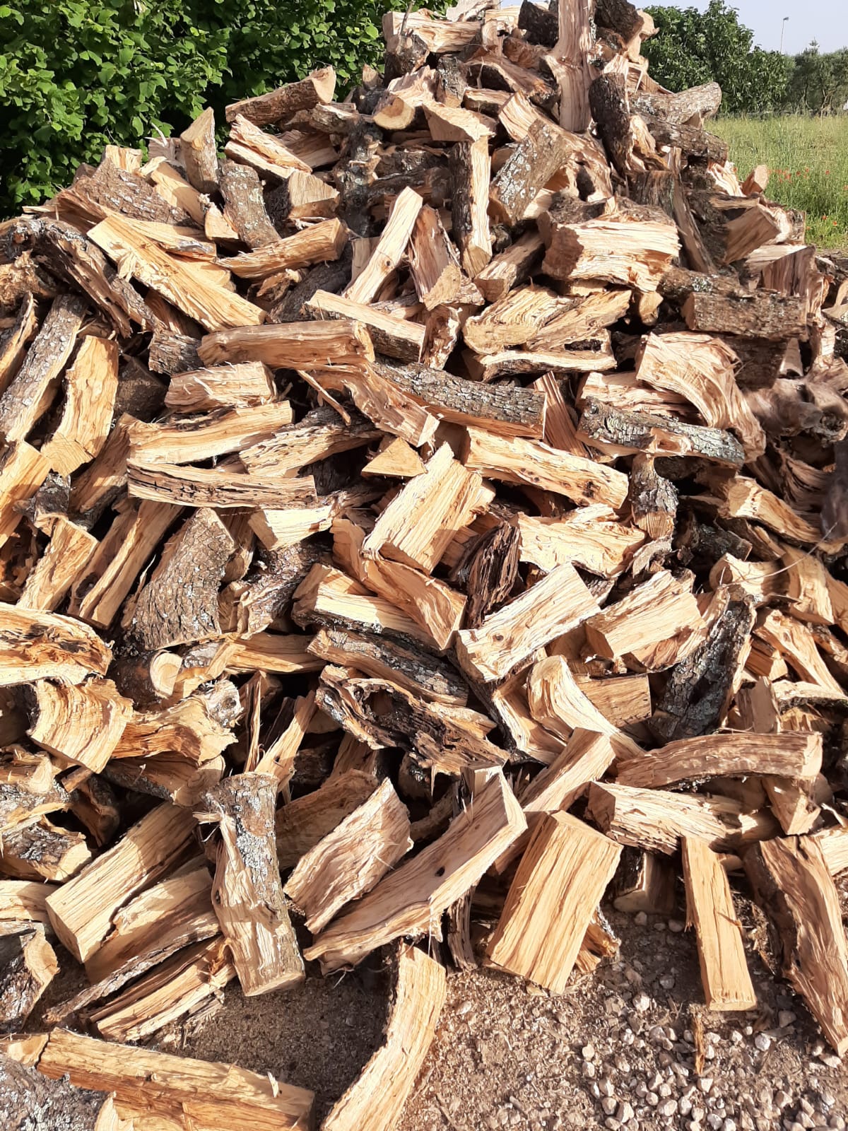 Catasta di legna da ardere spaccata, per lo più marrone e marrone chiaro, all'aperto.