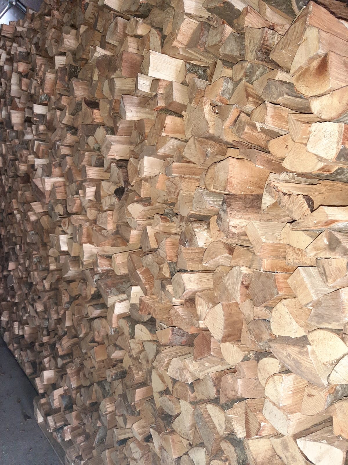 Catasta di legna da ardere accatastata, per lo più marrone e marrone chiaro, che riempie una parete.
