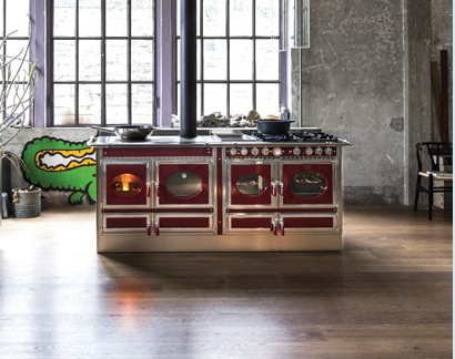 Cucina industriale rossa e argento con forno, piano cottura e camino nero in uno spazio in stile loft.