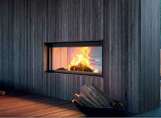 Camino con ceppi ardenti incastonato in una parete rivestita in legno; in primo piano c'è una ciotola piena di ceppi.