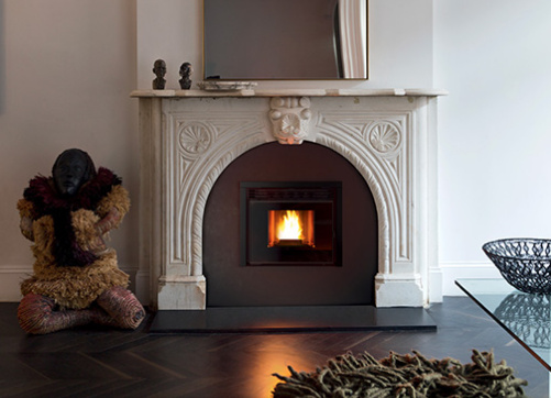 Camino con fuoco acceso, opere d'arte decorative e pavimento in legno scuro.